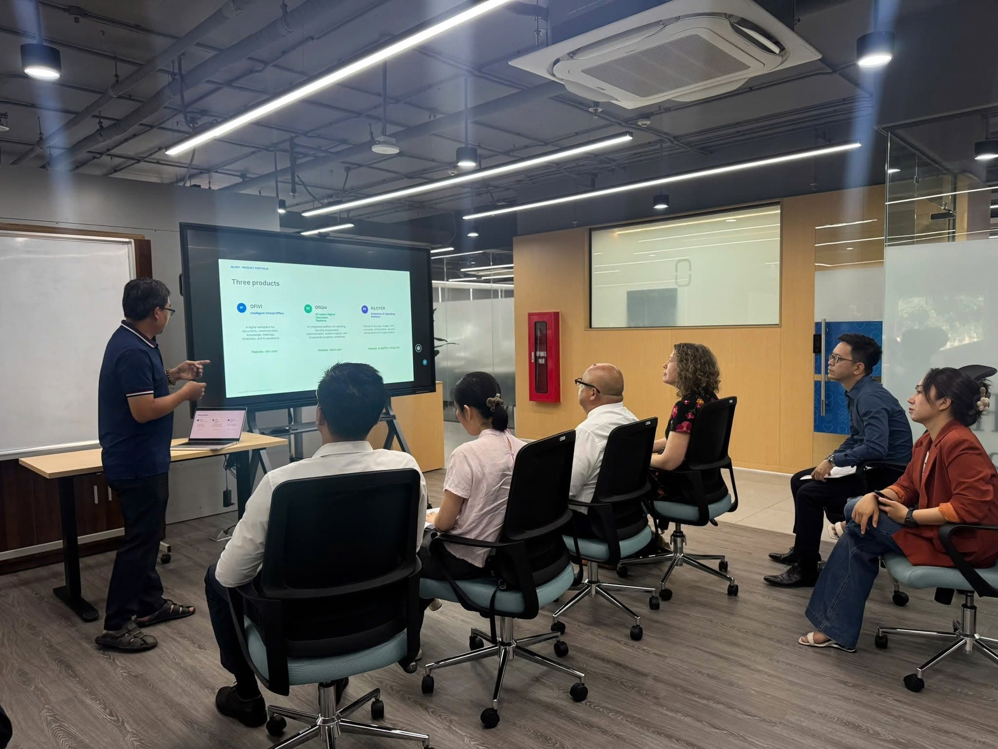 An AILOGY representative introduces three technology products to the visiting delegates.
