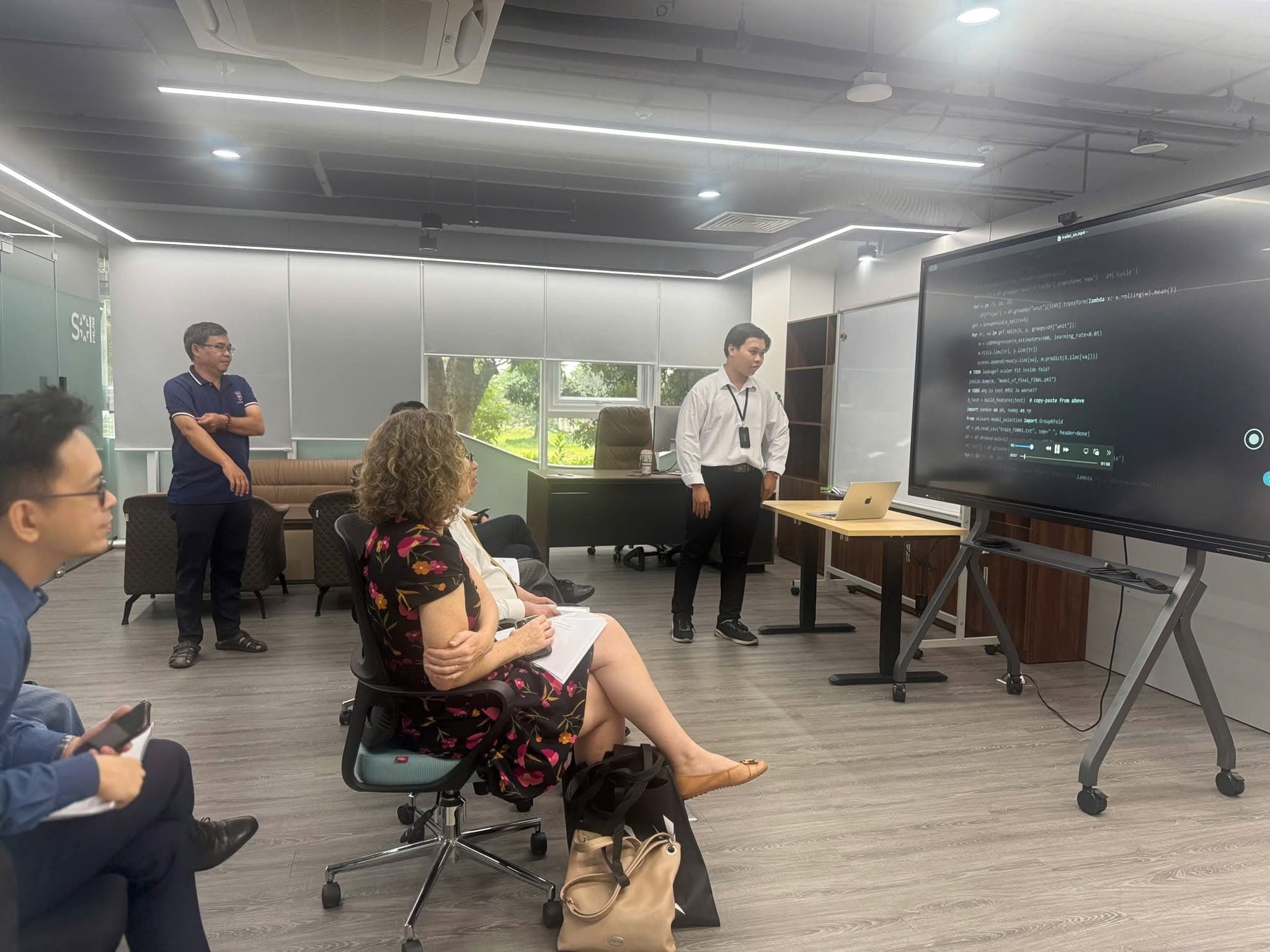 An AILOGY engineer demonstrates technology on a large screen for the delegation.